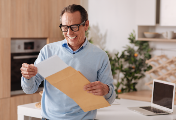 energetic-upbeat-elderly-businessman-sitting-home-while-enjoying-morning-routine-getting-letter-from-envelope